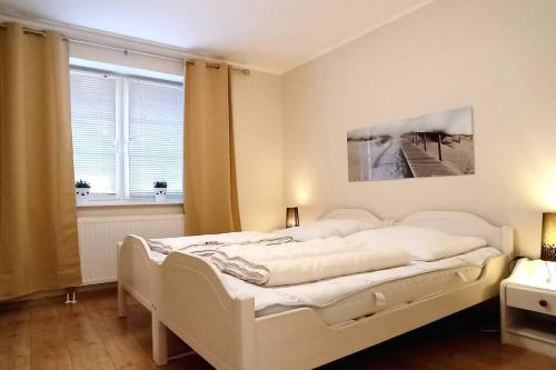 Una cama blanca en una habitación con ventana. en Wellness & Naturstrand (in 800 m), inkl. Pool, en Hof Barendorf