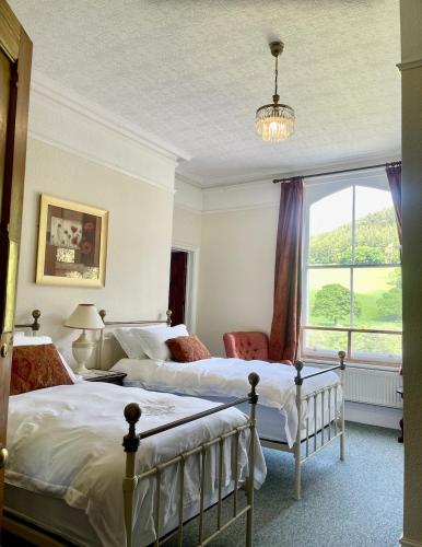 a bedroom with two beds and a large window at The Buckley Arms in Dinas Mawddwy