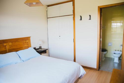 a bedroom with a bed and a bathroom with a toilet at Pajaro Azul in San Carlos de Bariloche