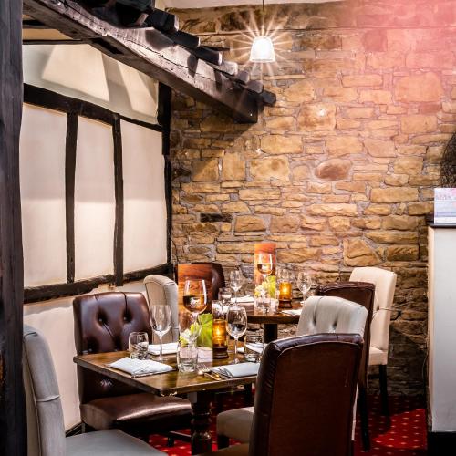 a dining room with tables and chairs and a stone wall at Last Drop Village Hotel & Spa in Bolton