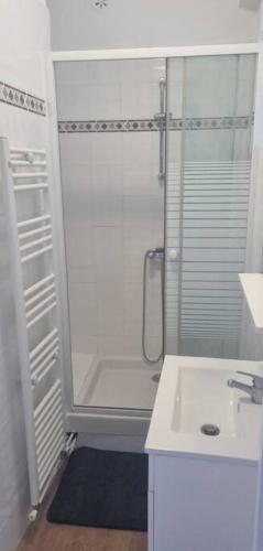 une salle de bain blanche avec une douche et un lavabo dans l'établissement chez Sandy, à Calais