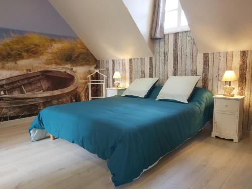 a bedroom with a blue bed with a painting on the wall at le bonheur des plumes in Montmartin-en-Graignes