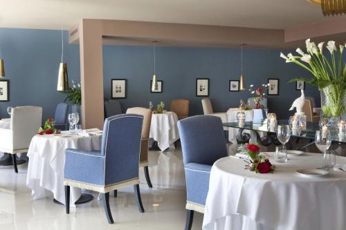 a restaurant with white tables and blue chairs and flowers at Cala del Porto Punta Ala - Preferred Hotels in Punta Ala