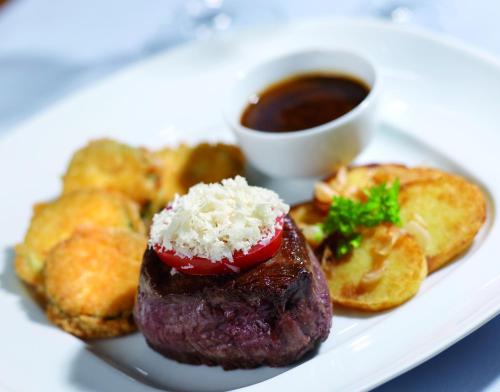a plate of food with a piece of meat and a cup of sauce at Seaside Residenz Hotel Chemnitz in Chemnitz
