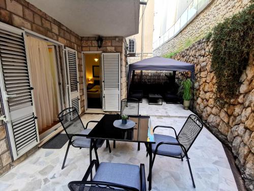 a patio with a table and chairs and a stone wall at Apartment Tatiana in Dubrovnik