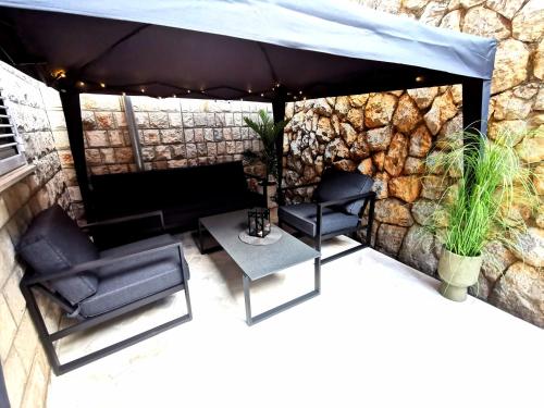 a stone wall with two chairs and a blue umbrella at Apartment Tatiana in Dubrovnik