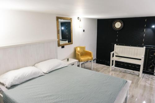 ein Schlafzimmer mit einem Bett, einem Stuhl und einer Uhr in der Unterkunft Deluxe dreams & spa Sabac in Šabac