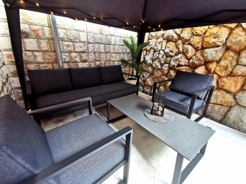 a patio with a couch and tables and a stone wall at Apartment Tatiana in Dubrovnik