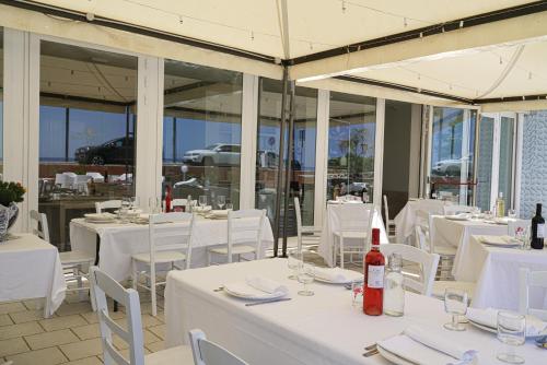 a restaurant with white tables and white chairs and bottles of wine at Hotel Rivabella in Davoli