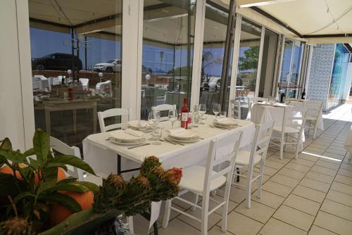 a white table with white chairs and wine bottles on it at Hotel Rivabella in Davoli