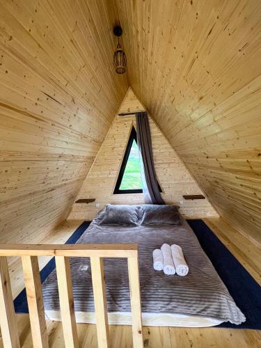 a bed in a wooden cabin with two slippers at Pine Chalet Kazbegi in Stepantsminda