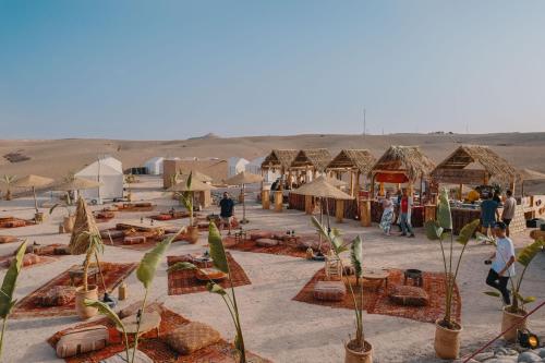 un grupo de tiendas y gente en el desierto en Selina Agafay Nomad Camp en El Karia