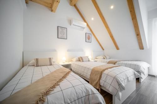 three beds in a room with white walls and wooden beams at Villa Nesa - beautiful guest house at continental Croatia with Outdoor swimming pool, Sauna and 3 Bedrooms in Plaški