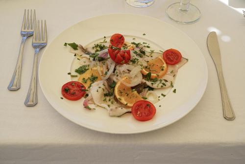 a white plate of food with tomatoes on a table at Hotel Rivabella in Davoli