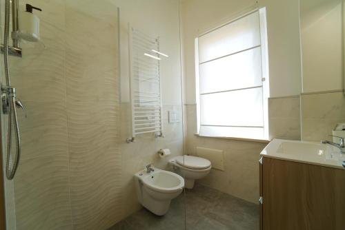 a bathroom with a toilet and a sink and a window at Hotel Rivabella in Davoli