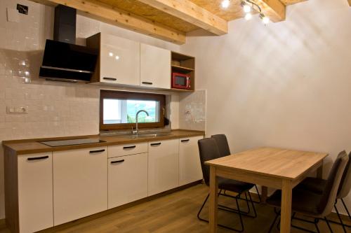 a kitchen with white cabinets and a table with chairs at Apartmaji Tanto Malovše in Črniče
