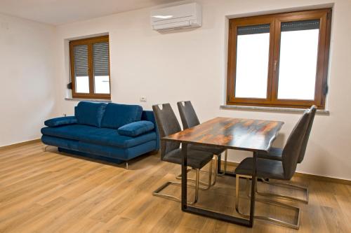 a living room with a table and a blue couch at Apartmaji Tanto Malovše in Črniče