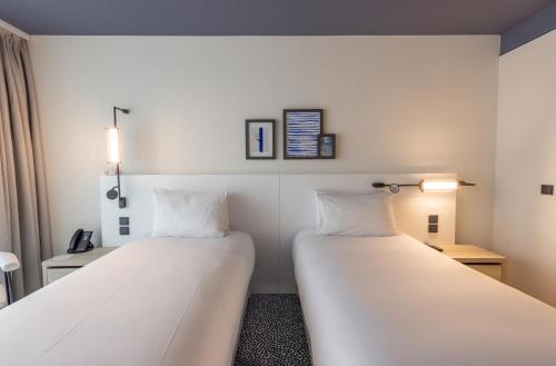 two beds in a small room with white sheets at Hotel Indigo Cagnes-sur-Mer by IHG in Cagnes-sur-Mer