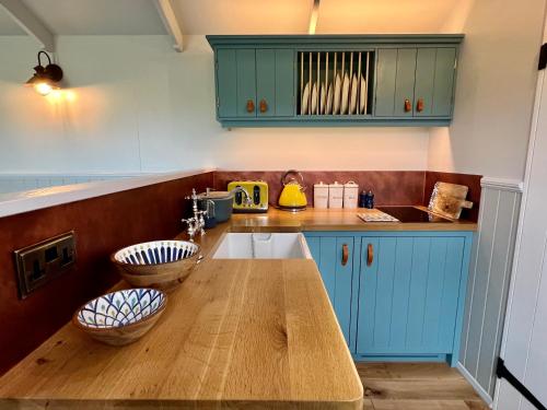 a kitchen with blue cabinets and a wooden counter top at Inglewood Shepherd's Huts in Penrith