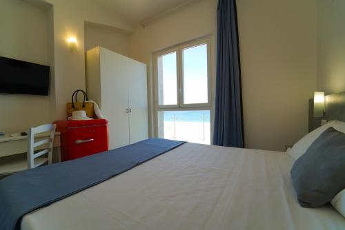 a bedroom with a large white bed with a window at Hotel Rivabella in Davoli