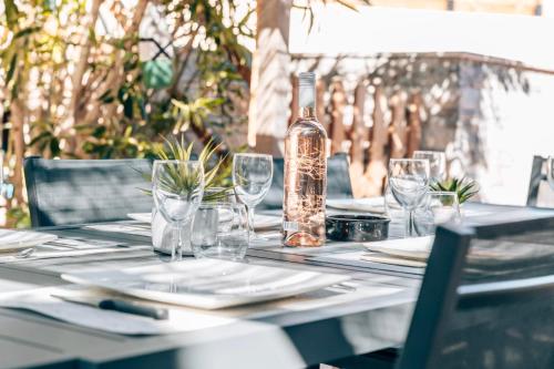 ein Tisch mit einer Flasche Wein und Gläsern darauf in der Unterkunft Maison Familiale avec Piscine Privée, plage à pied, Frais Obligatoires à régler à l'arrivée, Linge 15e par pers & Ménage 70e par séjour voir profil Mandatory fees in cash to be paid on arrival linen 15e per person 70e housekeeping per stay in Sainte-Maxime