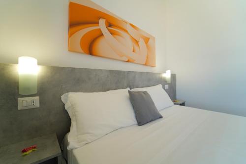 a bedroom with a white bed and a painting on the wall at Hotel Rivabella in Davoli