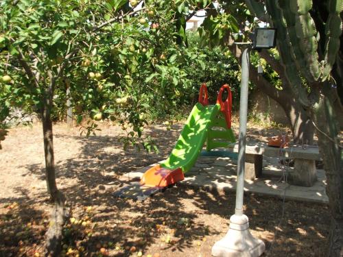 a plastic dinosaur sitting next to a bench under an apple tree at Villa Rosa in Modica