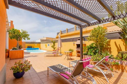 patio z krzesłami i basenem w obiekcie Villa Bella Lucia Luxury 2 w Corralejo