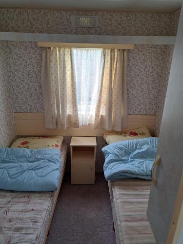 two beds in a room with a window at Mobilūs nameliai 'Zelma' in Palanga