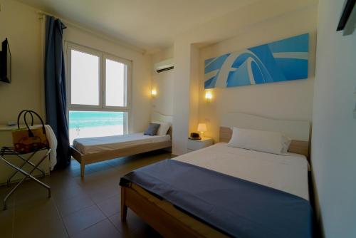a bedroom with two beds and a window with the ocean at Hotel Rivabella in Davoli