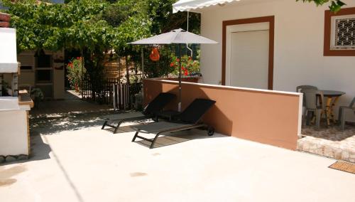 two chairs and an umbrella on a patio at KIKI Stegna in Archangelos