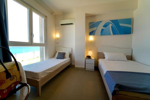 two beds in a room with a view of the beach at Hotel Rivabella in Davoli