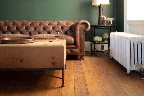 a living room with a brown couch and a table at OneSixtyFive, The Inn on Park Row in Brunswick