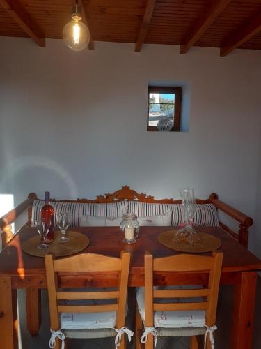 a wooden table with two chairs and wine glasses on it at Drougas' Windmill in Plaka Milou