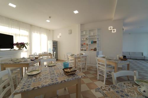 a living room with tables and chairs and a kitchen at Hotel Rivabella in Davoli