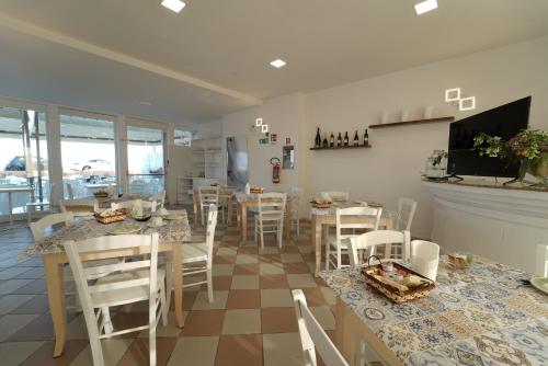 a restaurant with white chairs and tables and a counter at Hotel Rivabella in Davoli