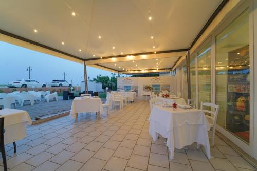 a restaurant with white tables and white chairs at Hotel Rivabella in Davoli