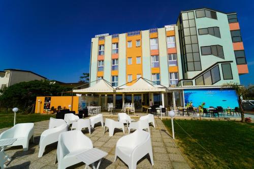 a group of white chairs and tables in front of a building at Hotel Rivabella in Davoli