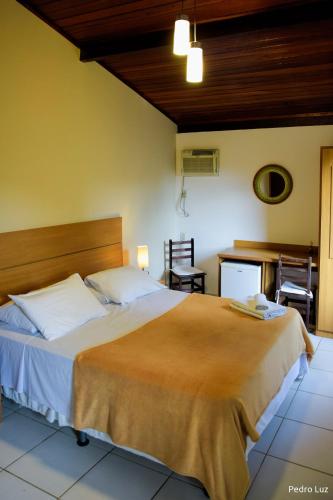 a bedroom with a large bed and a desk at Pousada Valle dos Pássaros in Penedo