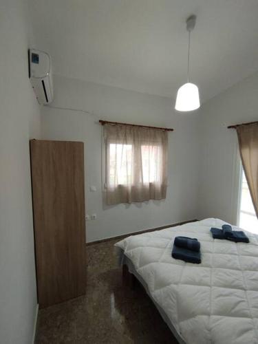 a bedroom with a white bed and a wooden cabinet at Διαμέρισμα κοντά στην θάλασσα in Arkoudi