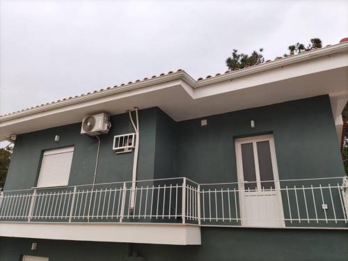 a green house with a balcony on the side of it at Διαμέρισμα κοντά στην θάλασσα in Arkoudi
