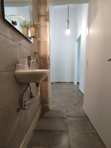 a bathroom with a sink and a mirror and a hallway at Διαμέρισμα κοντά στην θάλασσα in Arkoudi