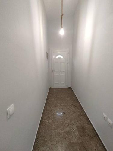 an empty hallway with a white door and a room with a floor at Διαμέρισμα κοντά στην θάλασσα in Arkoudi