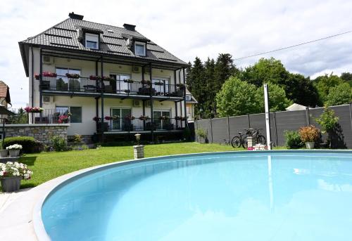 a house with a swimming pool in front of a house at Enjoyit Rooms in Velden am Wörthersee