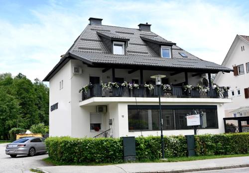 a white building with a balcony with flowers on it at Enjoyit Rooms in Velden am Wörthersee