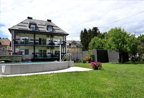 a house with a yard with a pool in front of it at Enjoyit Rooms in Velden am Wörthersee