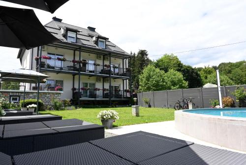 a house with a swimming pool in front of a building at Enjoyit Rooms in Velden am Wörthersee