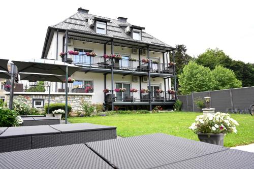 a large house with balconies and tables in a yard at Enjoyit Rooms in Velden am Wörthersee