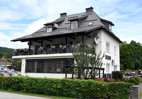 a white house with a black roof at Enjoyit Rooms in Velden am Wörthersee