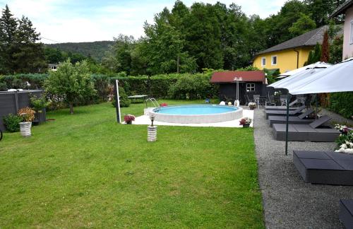 a backyard with a swimming pool and green grass at Enjoyit Rooms in Velden am Wörthersee